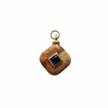 Charm de corcho natural con piedra azul marino sobre fondo blanco puro