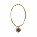 Collar dorado Roar con medallón circular de león, halo brillante y perla blanca sobre fondo blanco puro